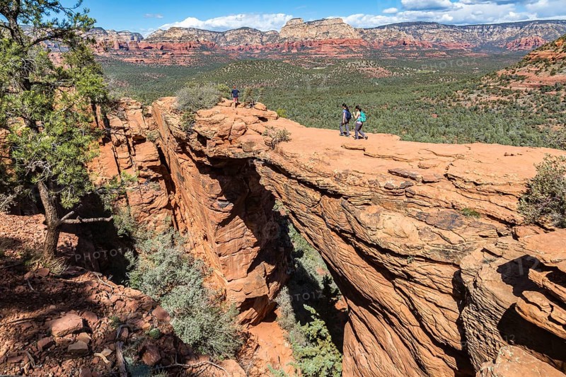 Hikers cross the Devil's Bridge natural arch along the Devil's Bridge Trail in Sedona, Arizona, USA, North America