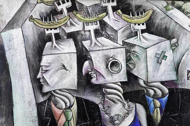 Graffiti on the Berlin Wall in the East Side Gallery, Berlin, Germany, Europe, Surrealist artwork with futuristic, masked heads and yellow bananas balanced on them, in a collective-dystopian style, East Side Gallery, Warschauer Strasse, Europe