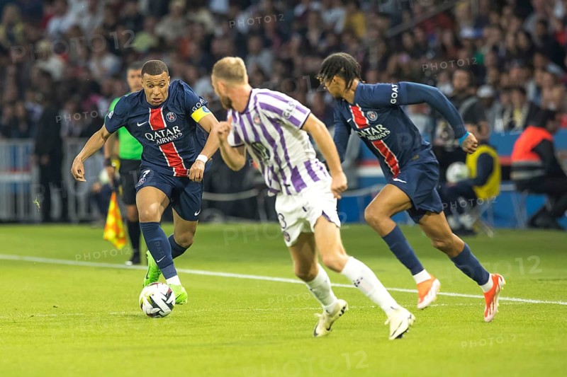 Football match, captain Kylian MBAPPE' Paris St. Germain left on the ball, a player of FC Toulouse and Bradley BARCOLA Paris St. Germain right watching him tensely while running, Parc des Princes football stadium, Paris, France, Europe