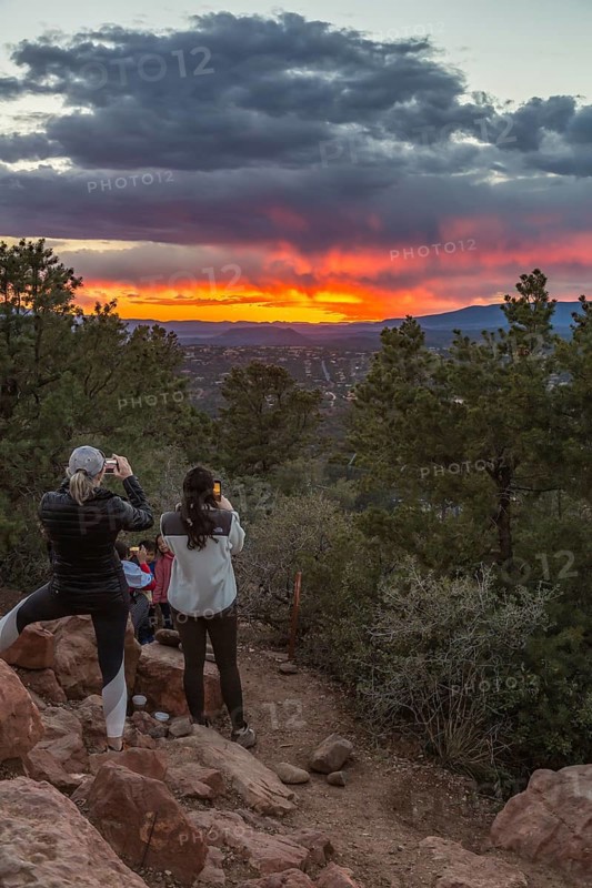 Young women photograhing the sunset over the city of Sedona, Arizona with cell phone cameras, USA, North America
