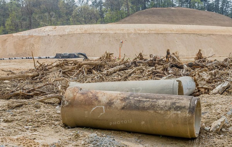 Old dirty concrete culvert sections on ground in front of tree branches at construction site in Daejeon, South Korea, Asia