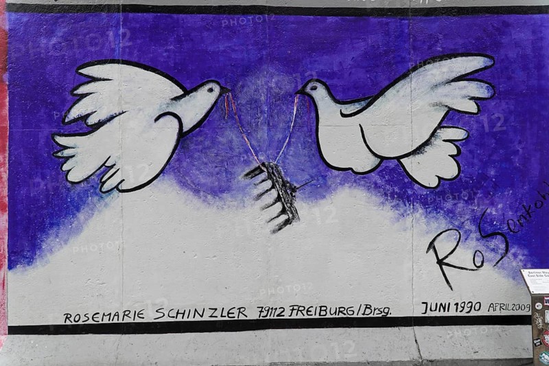 Rosemarie Schinzler, Doves of Peace on a Remnant of the Berlin Wall, Painting by Rosemarie Schinzler, East Side Gallery, Graffiti on the Berlin Wall in the East Side Gallery, Berlin, Germany, Europe, Graffiti with two white doves of peace holding a black object in a blue background, Warschauer Strasse, Europe