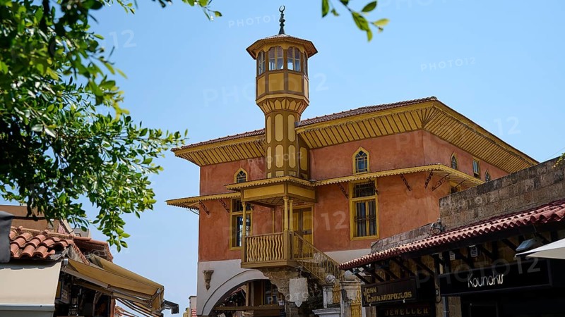 Mehmet Aga Mosque, Historic building with striking tower, surrounded by shops under sunny skies, Rhodes Old Town, Rhodes Town, Rhodes, Dodecanese, Greek Islands, Greece, Europe