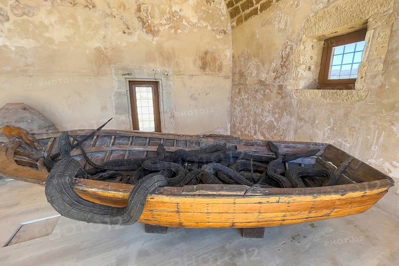 Photo of artwork by Museum of Contemporary Art Refugee boat of migrants and seven snakes made of steel wire, artist Kalliopi Lemos, title of artwork Wooden boat with seven snakes, historical fortress Fortetza Fortezza of Rethymno built by Republic of Venice in 16th century in northwest of old town of Rethymno on rocky hill Paleokastro on north coast of island Crete, Rethymno, Crete, Greece, Europe