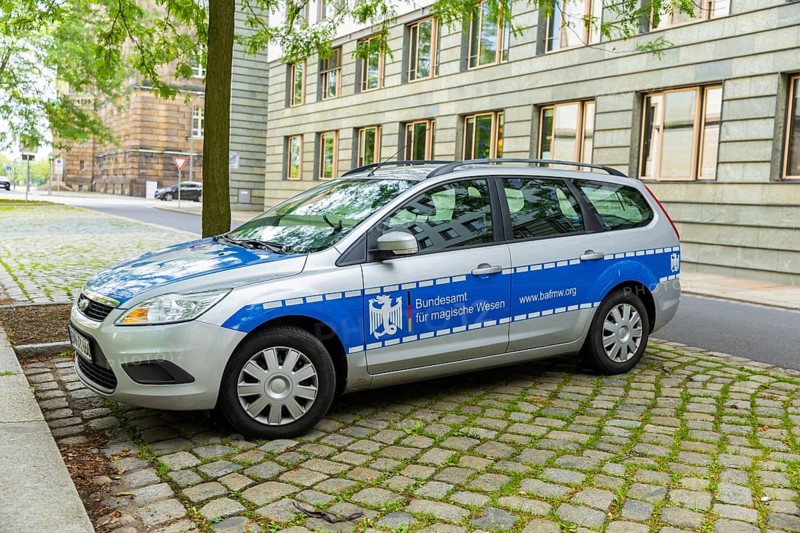 A car similar to a police car advertising a bookshop is parked in the government district of Dresden. The text Federal Office for Magical Creatures. www.bafmw.org, Dresden, Saxony, Germany, Europe