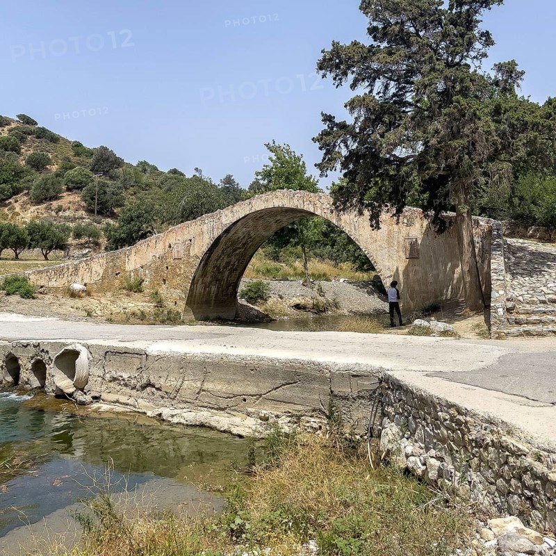 Classical arch bridge in Venetian architectural style made of stone Venetian Great Old Bridge 19th century stone bridge built in 1850 in Ottoman times over the middle reaches of the Megalopotamos River near Preveli, in front of it modern flat river crossing on the left with concrete pipes Tubes for water flow, Agios Vasilios, Crete, Greece, Europe