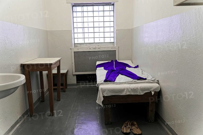 Simply furnished prison cell with bed and clothes. Small windows and cold lighting, Berlin-Hohenschoenhausen Memorial, former headquarters, Stasi remand centre, Berlin, Germany, Europe