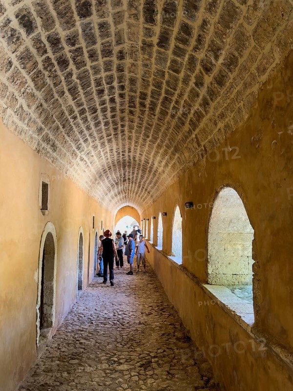 Archway with left doors to former monastery cell monk cells in the background tourists in UNESCO World Heritage Site historical orthodox monastery Moni Arkadi Arkadi monastery from early Middle Ages, important national monument national shrine on Crete island, Arkadi, Armnatos, Crete, Greece, Europe