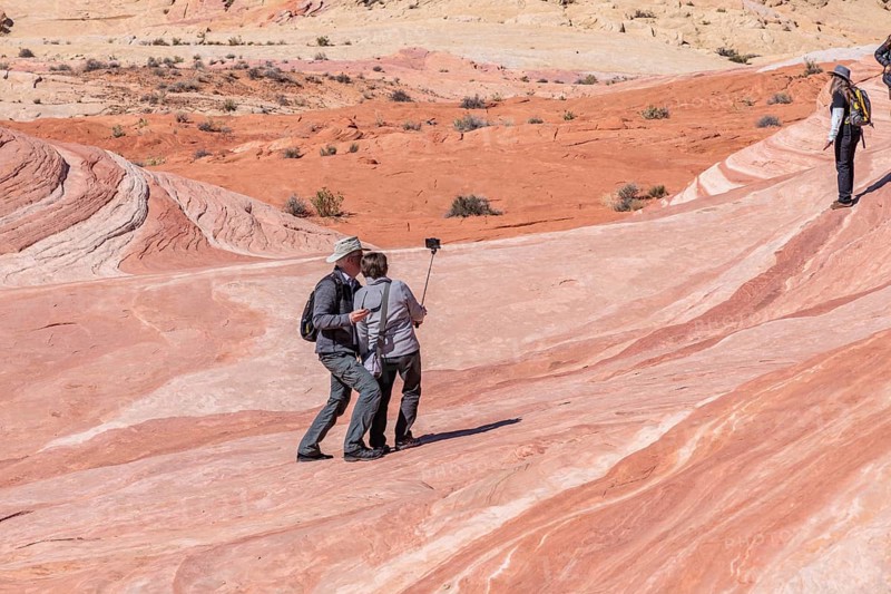 Couple use selfy stick for picture on a layered sandstone rock formation in the Fire Wave area of Valley of Fire State Park near Overton, Nevada, United States of America, USA, North America