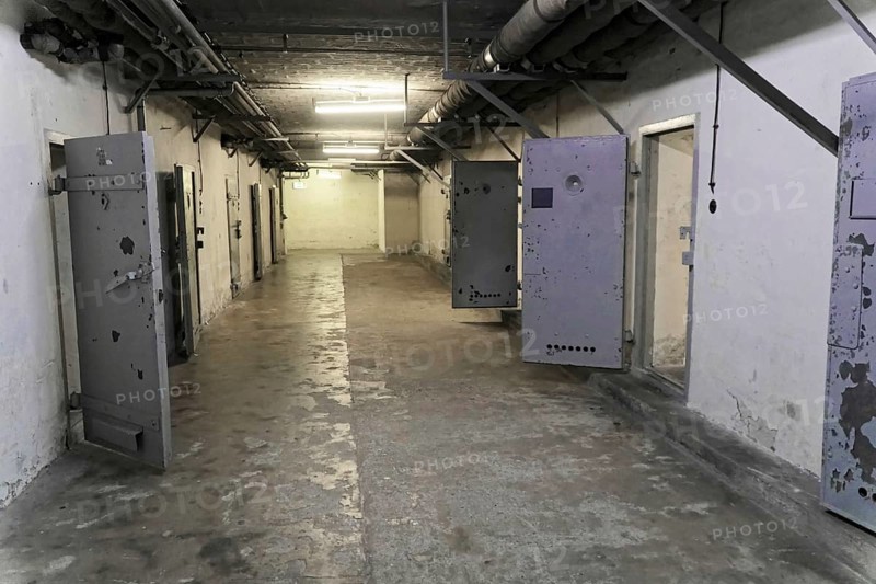Long prison corridor with open metal doors and grey walls. Gloomy lighting, cold atmosphere, Berlin-Hohenschoenhausen Memorial, former headquarters, Stasi remand centre, Berlin, Germany, Europe