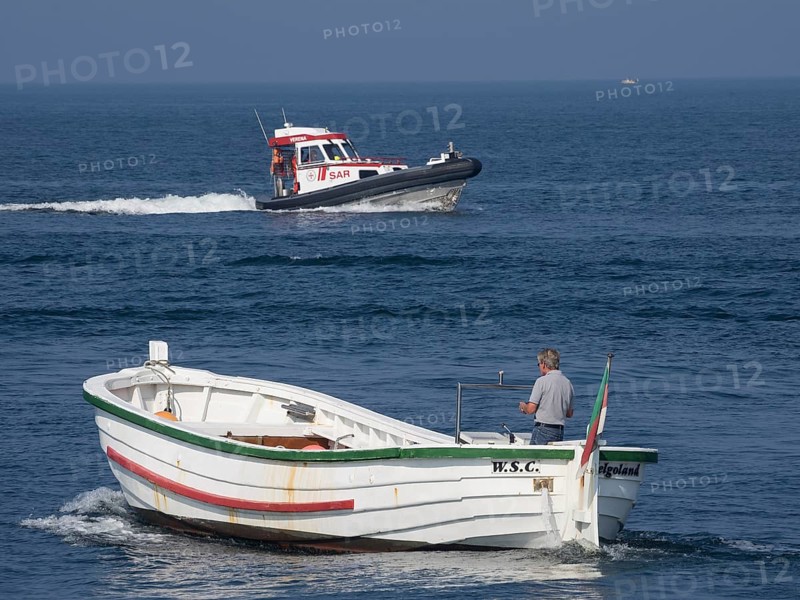 A white boat with a man and a SAR lifeboat at sea, Helgoland, Germany, Europe