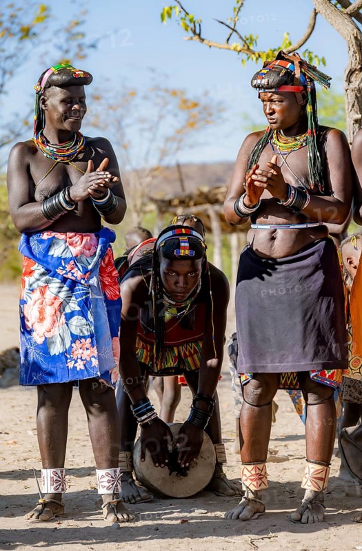 Hakaona woman with traditional kapapo hairstyle, clapping and drumming, Angolan tribe of the Hakaona, near Opuwo, Kunene, Namibia, Africa