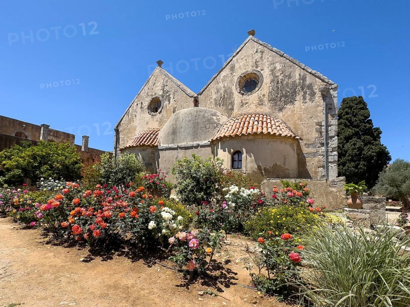 View of rear wall of double-aisled church building Church of Arkadi Monastery with double apse in the foreground blooming flowers and shrubs in UNESCO World Heritage Site Orthodox Monastery of Moni Arkadi Arkadi Monastery from early Middle Ages, important national monument national shrine on Crete island, Arkadi, Armnatos, Crete, Greece, Europe