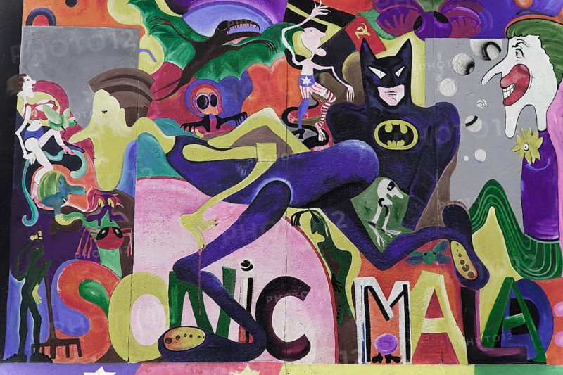 Graffiti on the Berlin Wall in the East Side Gallery, Berlin, Germany, Europe, A surrealistic graffiti with a Batman figure and various colourful comic elements in the background, East Side Gallery, Warschauer Strasse, Europe