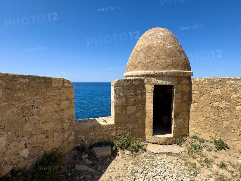 Round watchtower and wall with crenellated gap for guns one of 10 round watchtowers of historic fortress Fortetza Fortezza of Rethymno built by Republic of Venice in 16th century in northwest of old town of Rethymno on rocky hill Paleokastro on north coast of island Crete, in background Aegean Sea Aegean Cretan Sea Mediterranean, Rethymno, Crete, Greece, Europe