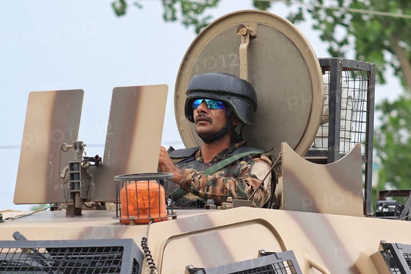 A soldier in an armored vehicle wearing a helmet and sunglasses, leaving encounter site in Pulwama, Jammu and Kashmir, India, Asia