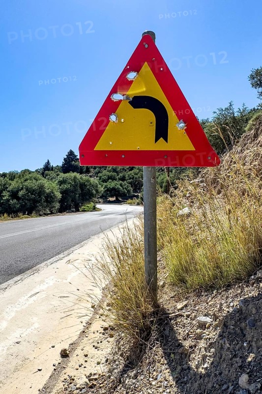 Bullet holes in road sign is target for target practice of bullets shot through, Crete, Greece, Europe