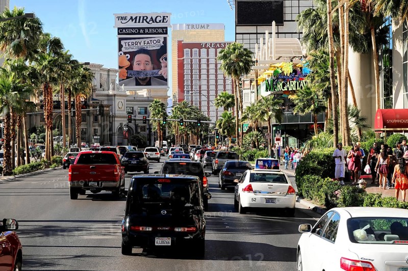 Las Vegas, Nevada, USA, North America, Street traffic with several cars and palm trees along the Las Vegas Strip, lined with tall buildings and billboards, Las Vegas Strip, North America