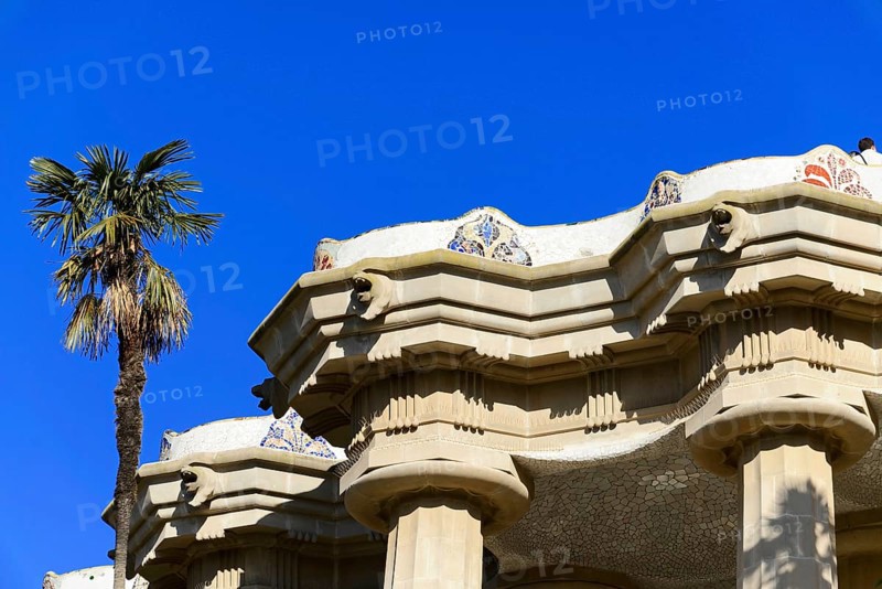 Antoni Gaudi, Park Guell, UNESCO World Heritage Site, Barcelona, Catalonia, Spain, Europe, Historic architecture with imposing columns and a palm tree in the park under a sunny sky, Europe