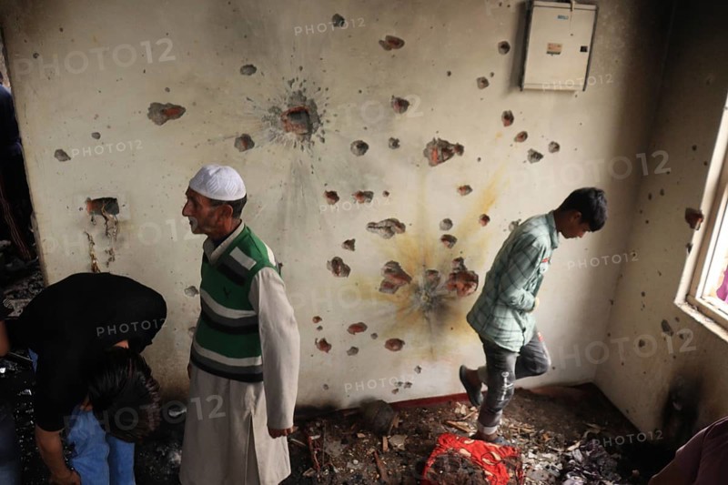 People in a room with a wall full of bullet holes, depicting the aftermath of violence, Encounter, Pulwama, Jammu and Kashmir, India, Asia