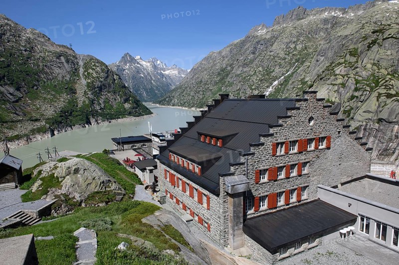 View of Grimsel Hospice Grimselhospiz with stepped gable Gable with stepped contour and red shutters on pass road Alpine Pass Pass in Swiss Alps from to Grimselpass, behind it reservoir Grimselsee at Grimsel in Bernese Oberland, Guttanen, Canton Bern, Switzerland, Europe