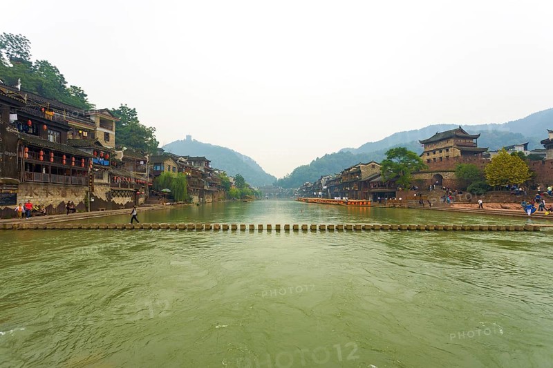 Fenghuang, China, September 10, 2007: A stepping stone bridge spans the Tuojiang River which cuts through the center of the beautiful traditional village and tourist destination of Fenghuang, Asia
