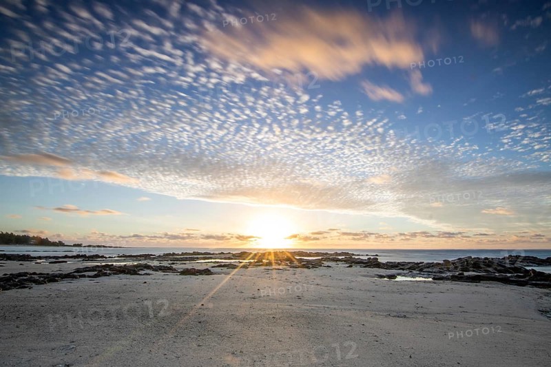 Sunrise over the sea with gentle waves. Sandy beach with lava rocks and blue water alternating with blue water. Island in the Indian Ocean, beach out of the blue, Trou d'Eau Douce, Mauritius, Africa