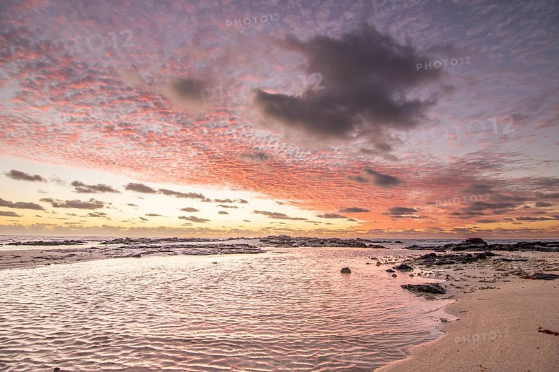 Sunrise over the sea with gentle waves. Sandy beach with lava rocks and blue water alternating with blue water. Island in the Indian Ocean, beach out of the blue, Trou d'Eau Douce, Mauritius, Africa