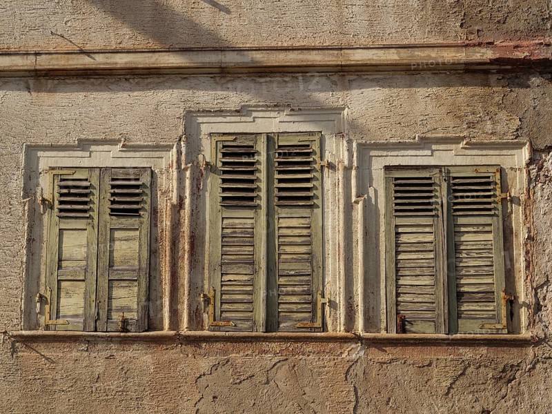 Three old windows with weathered green shutters on a ruined house wall, Kandel, Palatinate, Germany, Europe