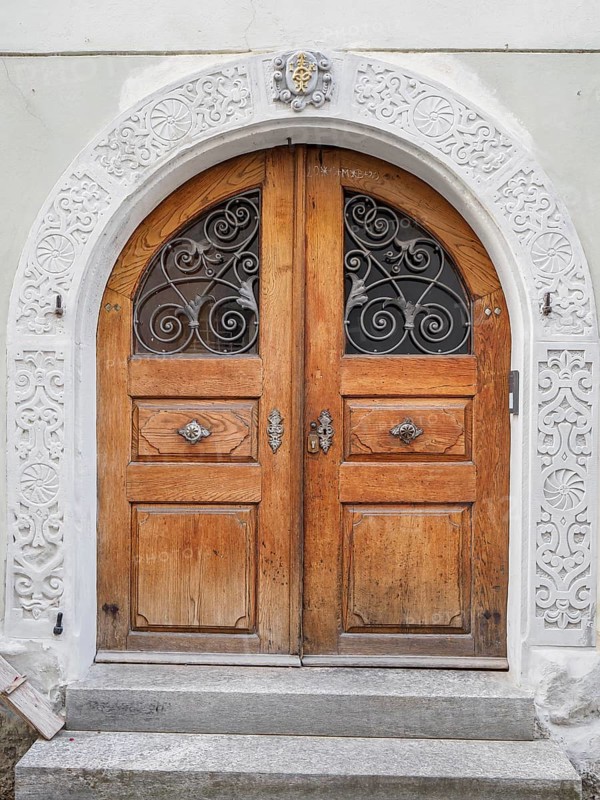 Antique wooden door with ornately carved archway and metal grilles in a historic building, lindau, bavaria, germany