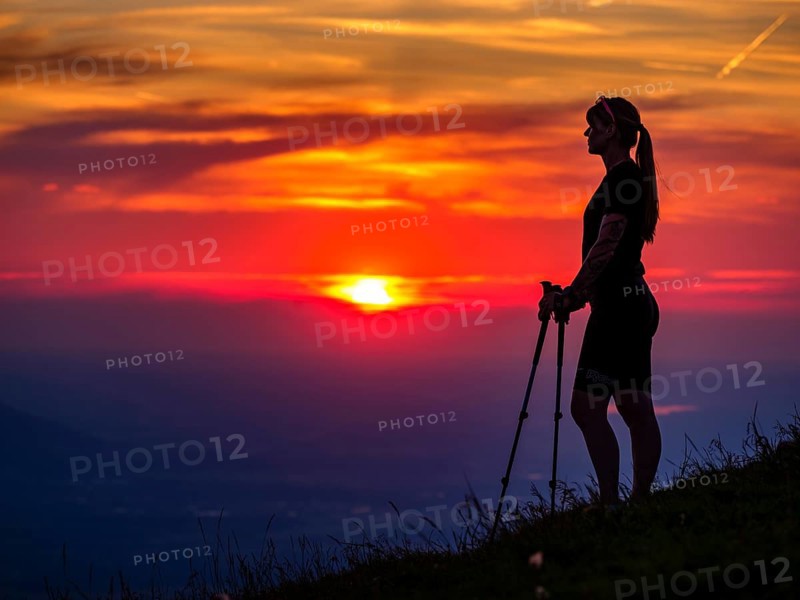 Silhouette of a young slender woman with hiking poles on a mountain meadow at sunset, Schlenken, Bad Vigaun, Salzburg province, Austria, Europe