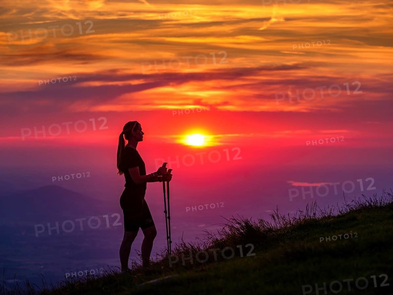 Silhouette of a young slender woman with hiking poles on a mountain meadow at sunset, Schlenken, Bad Vigaun, Salzburg province, Austria, Europe