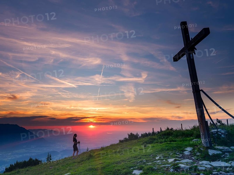 Young slim woman with hiking poles next to a summit cross at sunset, cirrus clouds in the sky, Schlenken, Bad Vigaun, Land Salzburg, Austria, Europe