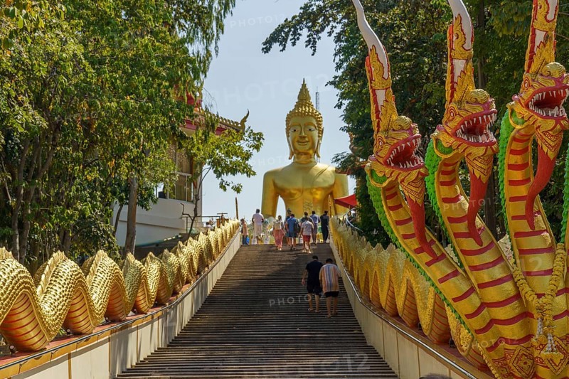Large golden Buddha statue at the end of a staircase, flanked by dragon statues and visited by people, Pattaya, Thailand, Asia