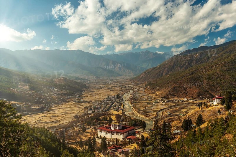 Sunrays through the clouds as the sun is setting over Paro