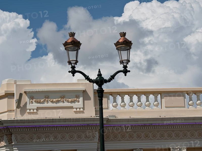 Historic street lamp in front of an old building with a sky full of clouds in the background, ajaccio, corsica, france