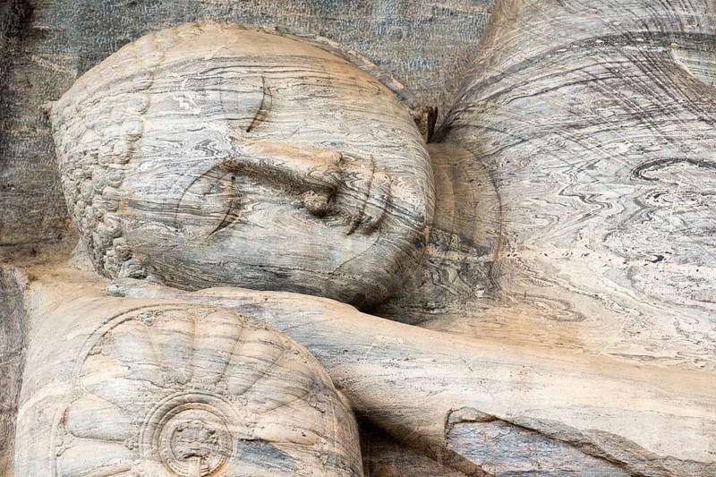 A closeup of the monolithic reclining Buddha statue, the Gal Viharaya, carved from a single piece of striated granite, at the ancient kingdom capitol of Polonnaruwa, Sri Lanka, Asia