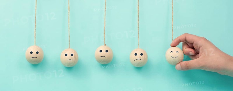 Happy smiling face spread happiness to sad faces, newton cradle concept, mental health and attitude, positive and negative mind, influence emotion, support and depression, pendulum balls