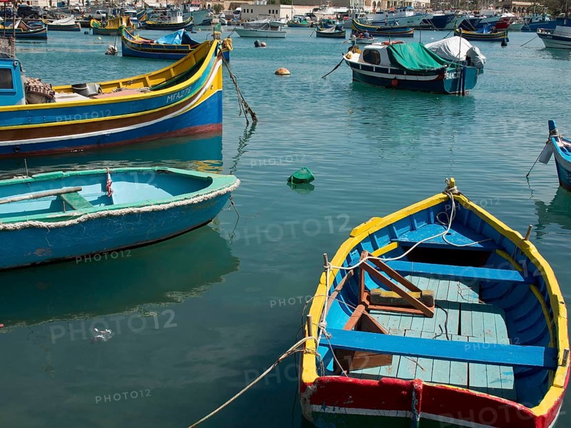 View of several colourful boats floating on the water in the harbour, marsaxlokk, mediterranean sea, malta