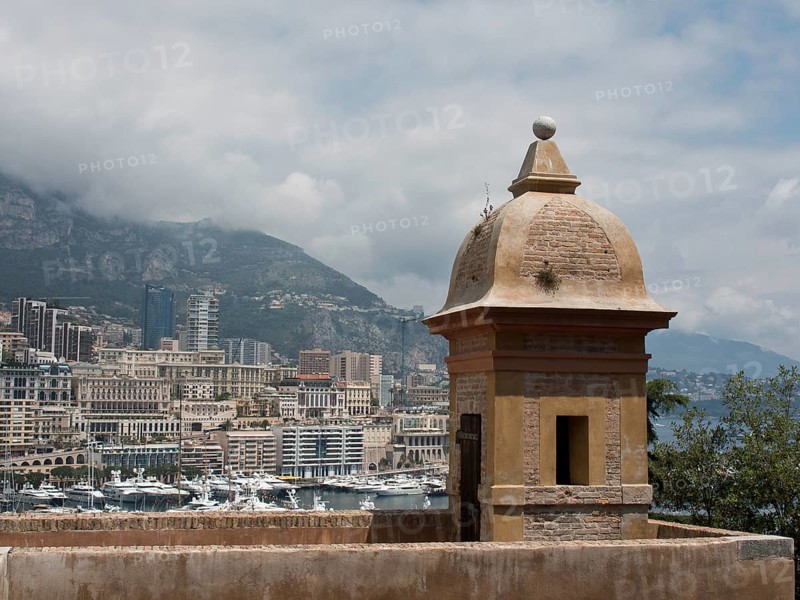 View of a harbour district with historic towers and a densely populated city, surrounded by mountains and clouds, monte carlo, monaco, france