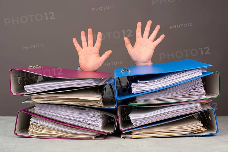 Exhausted tired worker, pile of file folders, hands up, burnout, stress and overworked, pressure at work