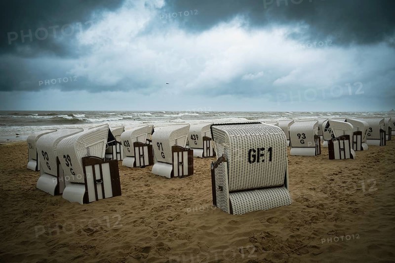 Roofed wicker beach chairs at the baltic sea beach, coast at the island of Usedom in Germany, storm and rain over the brackish water, high waves, storm warning
