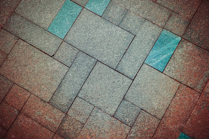 Geometric pattern of pavement tiles in blue and brown tones, creating a textured urban flooring design, background image