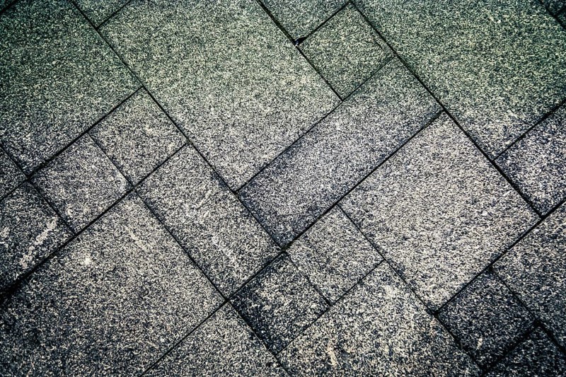 Gray concrete tiles arranged in a geometric pattern creating a rough and textured surface, background image
