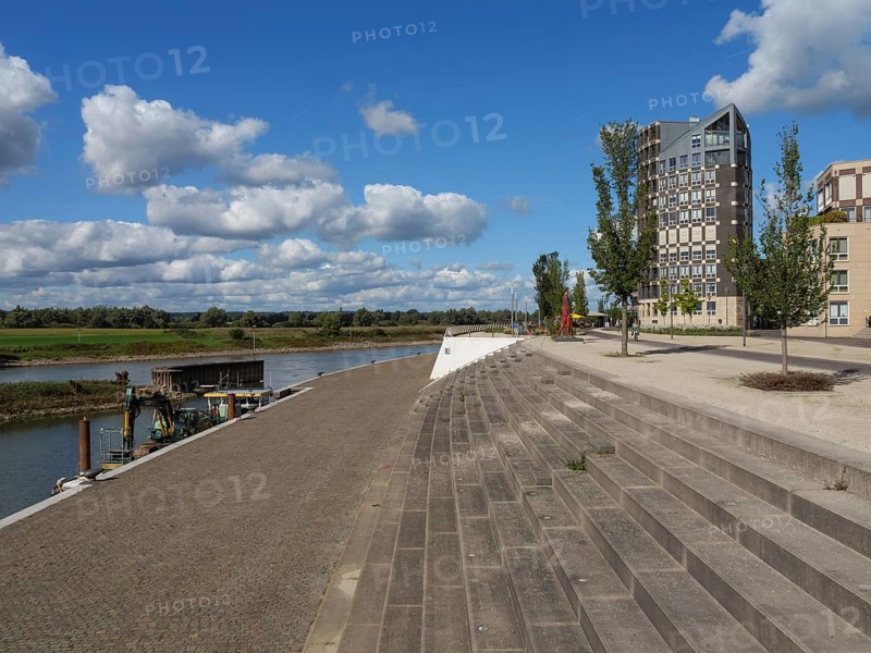 Riverbank with modern buildings in the background and a promenade, under a sky with small clouds, Doesburg, Gelderland, Netherlands