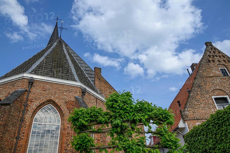 Red brick church with gothic architecture and high towers, someone in a village in good weather, Bredevoort, gelderlande, the netherlands