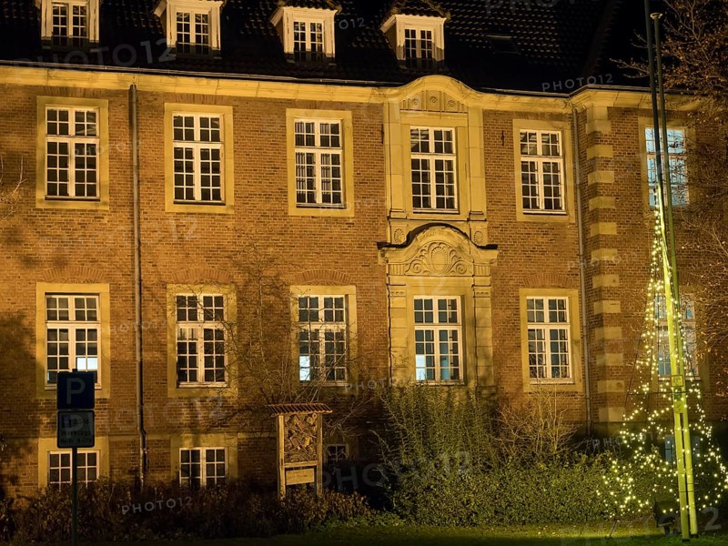 A historic building with illuminated windows at night. The warm light emphasises the details of the architecture, Borken, Münsterland, North Rhine-Westphalia, Germany, Europe