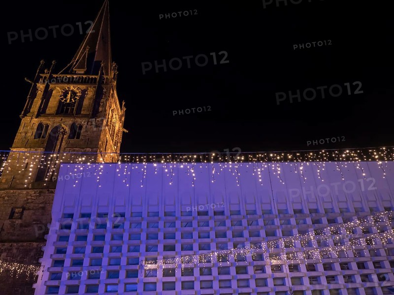An imposing church tower and a modern building side by side, with festive lighting at night, Ahaus, Münsterland, North Rhine-Westphalia, Germany, Europe
