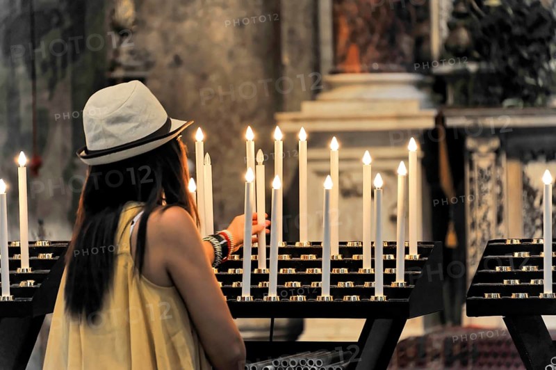 Interior view, Cathedral of Santa Maria Assunta, Pisa, Tuscany, Italy, Europe, A woman with a hat lights candles in silent prayer in a church, Europe