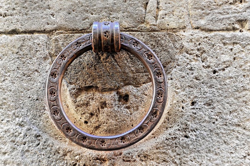 Volterra, Tuscany, Italy, Europe, Close-up of an antique metal door knocker on a stone wall, Europe